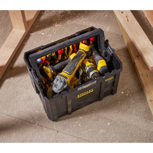 Stanley FMST1-75794 black tool box filled with yellow and black hand tools, top view, workshop setting.
