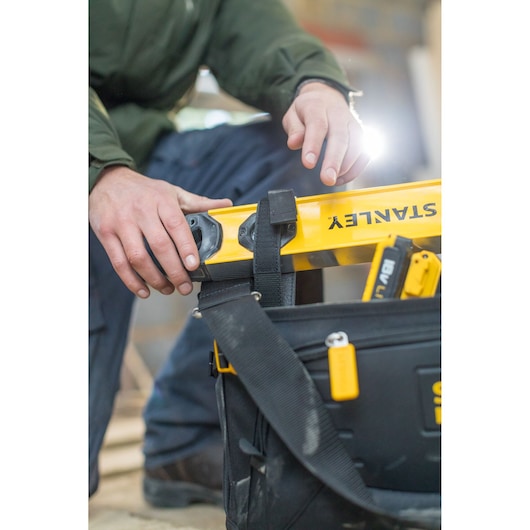 STANLEY FMST1-80146 tool bag with tools and yellow level, close-up, photographer captures use on site.