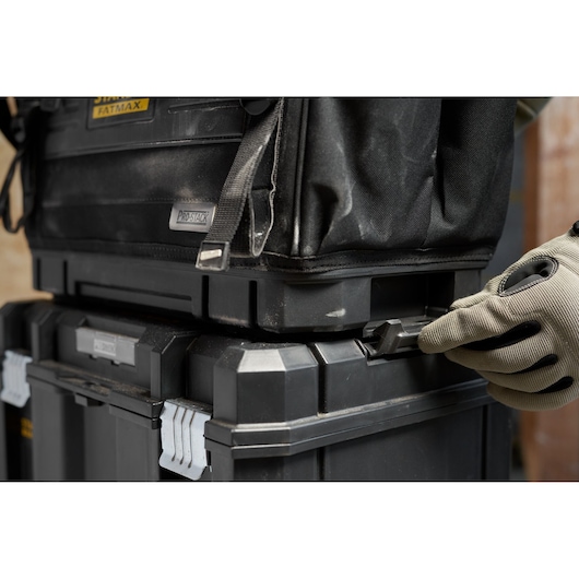 STANLEY FMST17626-1 stackable black toolboxes with side latch being handled, close-up angle.