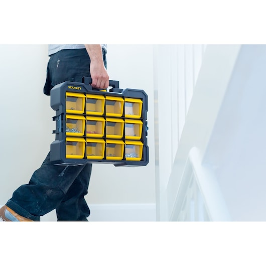 STANLEY FMST81077-1 organizer with yellow transparent bins, carried by hand indoors.