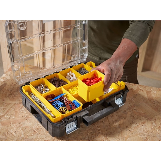STANLEY FMST82967-9 organizer box with removable yellow compartments holding assorted hardware, shown on a wooden table.