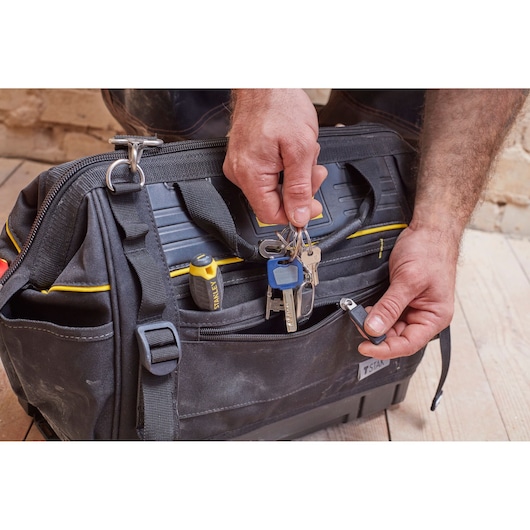 STANLEY FMST83297-1 tool bag, front angle, black with yellow accents, keys and screwdriver in pocket.