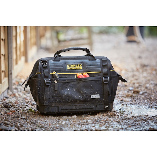STANLEY FMST83297-1 FATMAX tool bag with handles and front pockets, shown in wet outdoor setting.
