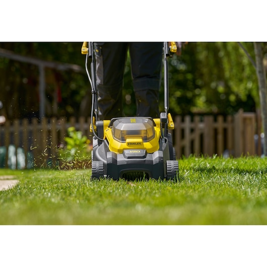 Photo of STANLEY SCMWP3401M1-XE cordless lawn mower on grass, front view showing yellow and black design.