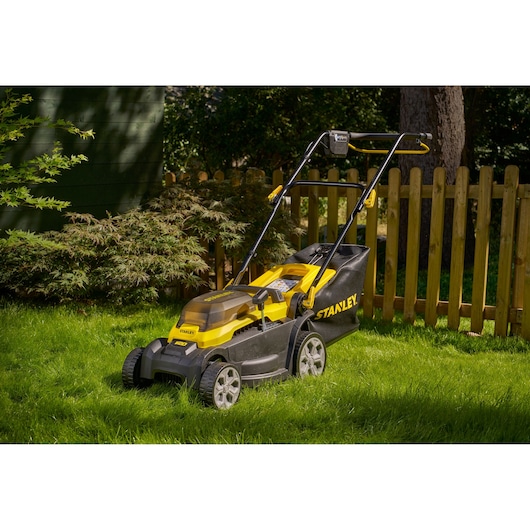 STANLEY SCMWP3401M1-XE lawn mower with yellow and black body on green lawn, photographed outdoors.