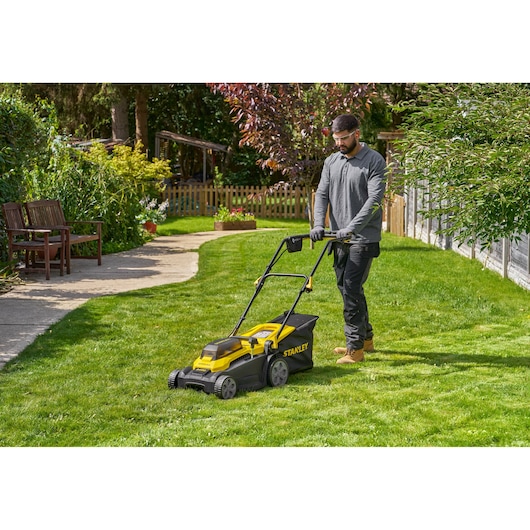 Photo of STANLEY SCMWP3701M2 lawn mower in use on a green lawn, outdoor garden setting.