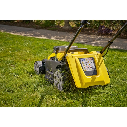 Photo of STANLEY SCMWP3701M2 lawn mower side view on grass with yellow and black body and large rear wheels.