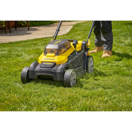 Photo of STANLEY SCMWP3701M2 lawn mower on grass, yellow and black cordless model with person mowing.