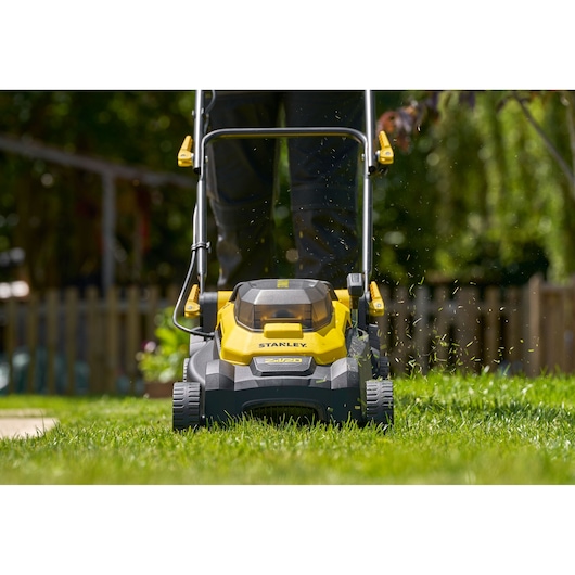 STANLEY SCMWP3701M2 cordless lawn mower front view cutting grass outdoors.
