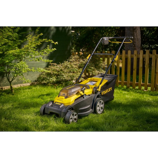 STANLEY SCMWP3701M2 lawn mower in yellow and black on grass, side angle, outdoor garden setting.
