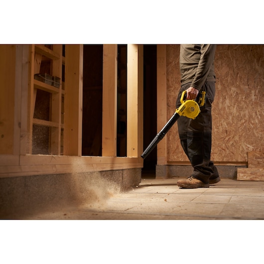 STANLEY SFMCBL01B blower in use on construction site, yellow cordless tool clearing dust from floor.