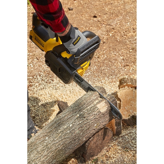 STANLEY SFMCCS630M1 chainsaw in use, cutting a log on forest floor, close-up of tool and bar.
