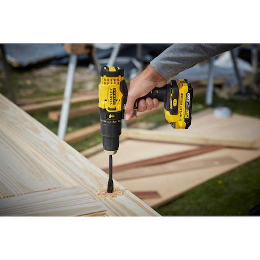STANLEY SFMCD711D11 cordless drill in use on wood, product photography outdoors.