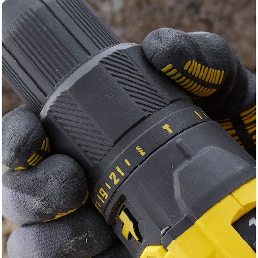Close-up photo of STANLEY SFMCD711D11 drill showing grip, adjustment ring, and settings, held by gloved hand.
