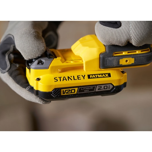 Photo of STANLEY SFMCD711D11 V20 Fatmax 2.0Ah lithium-ion battery held in gloved hands, close-up view.