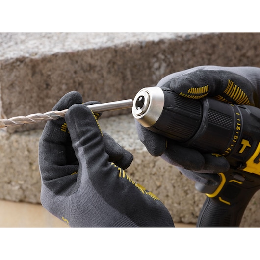 STANLEY SFMCD711D21 cordless drill, close-up side view, gloved hands inserting drill bit.
