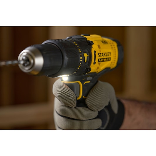 Stanley SFMCD711D21 cordless drill held in a gloved hand, close-up, yellow and black design.
