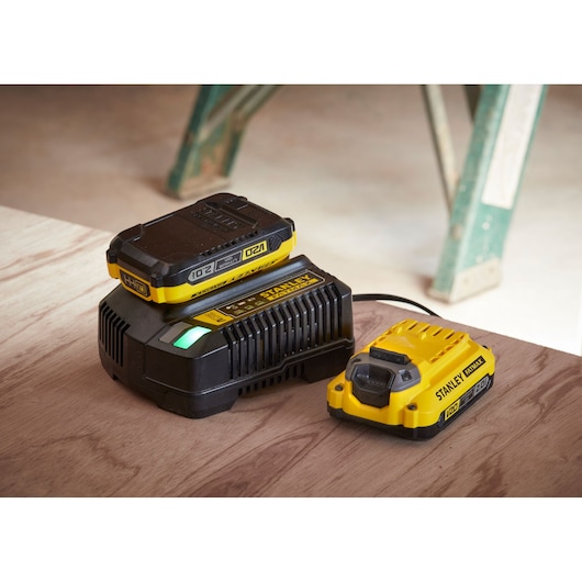 STANLEY SFMCD715D2K battery charger and battery pack on wooden surface, angled view.