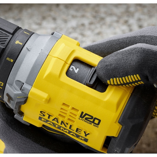 Photo of STANLEY SFMCD715M12 V20 FATMAX drill with glove hand adjusting speed switch, close-up.