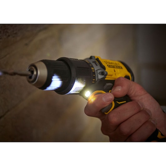 STANLEY SFMCD715M2K cordless drill in use, yellow and black, close-up with LED light on.