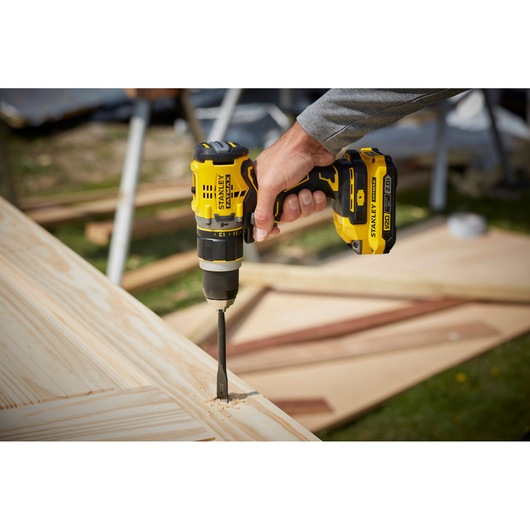 STANLEY SFMCD721D2K cordless drill in use on light wood outdoors, close-up view.