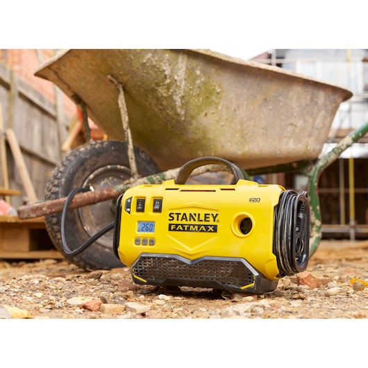 STANLEY SFMCE520B portable yellow inflator, FATMAX V20, on a work site with a wheelbarrow.