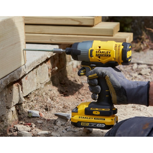 STANLEY SFMCF800D1K impact driver, yellow and black, being used to drill into wood outdoors.