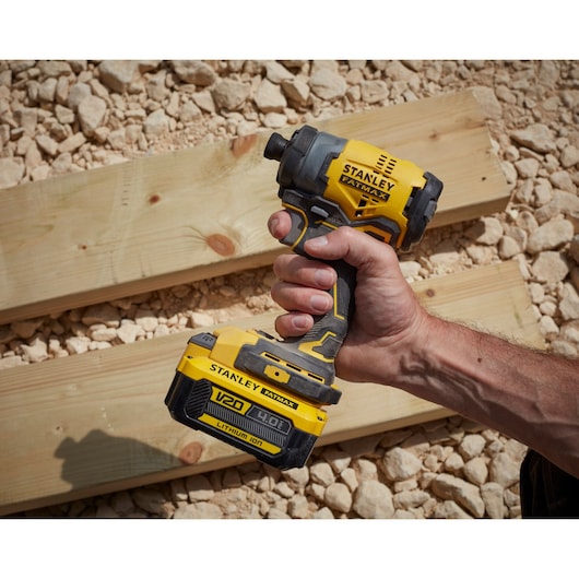 Stanley SFMCF810M1K cordless impact driver held in hand, yellow and black color, outdoor setting.