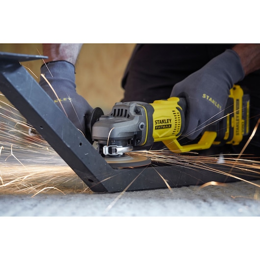 STANLEY SFMCG400M2K angle grinder in use on metal, close-up with sparks flying, user wearing gloves.