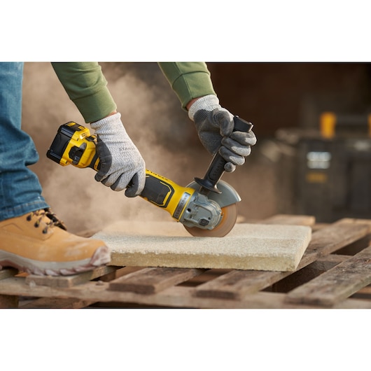 STANLEY SFMCG700M2K angle grinder in use cutting stone on a pallet, photography product category.