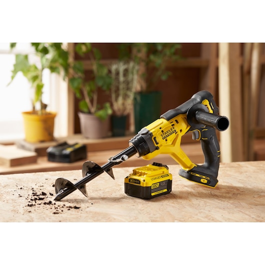 STANLEY SFMCGA75M1 cordless garden auger displayed with battery on a workbench, side angle.