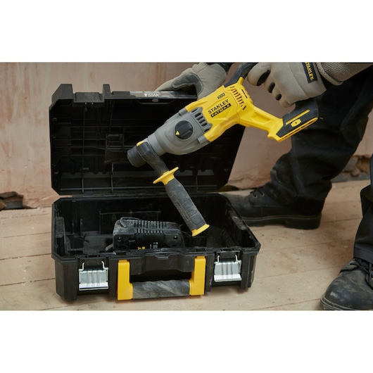 STANLEY SFMCH900M12 rotary hammer drill with side handle placed in open black and yellow carrying case, front angle.
