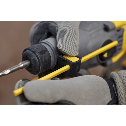 Photo of STANLEY SFMCH900M12 drill close-up, gloved hand adjusting yellow depth rod, photography angle from the side.