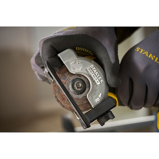 STANLEY SFMCM300B compact circular saw held with gloves, close-up of blade and guard.