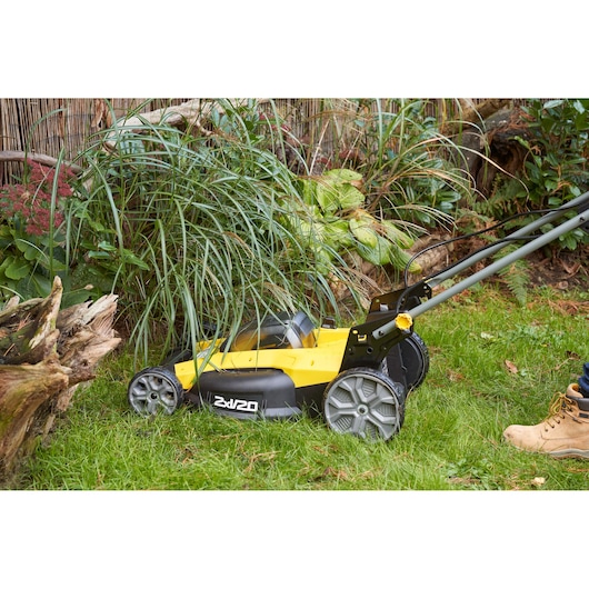 STANLEY SFMCMWS251M lawn mower side view cutting grass near plants outdoors.