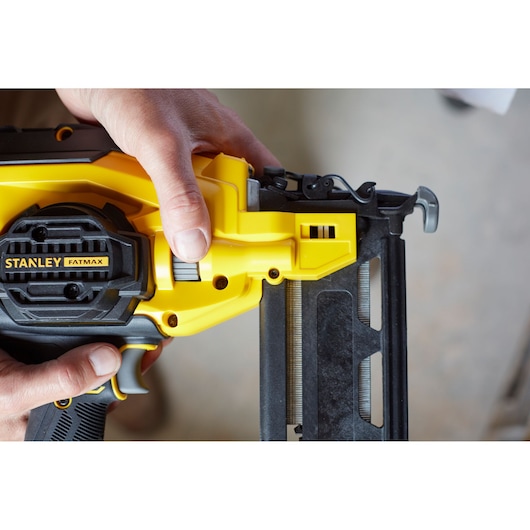 Close-up photo of STANLEY FATMAX SFMCN616B nail gun, yellow and black, being held by hand during use.