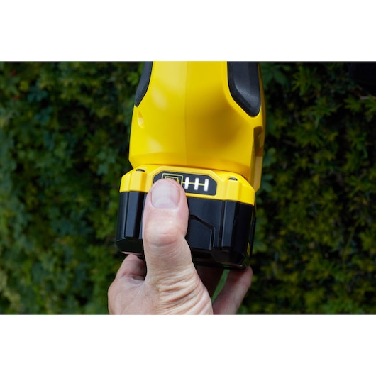 STANLEY SFMCPH845M1 cordless tool battery held in hand, close-up against outdoor greenery.