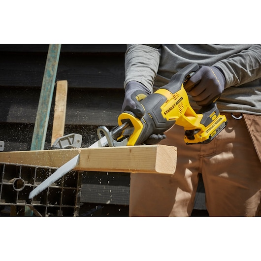 STANLEY SFMCS300B cordless reciprocating saw in use cutting wood, close-up view of power tool.