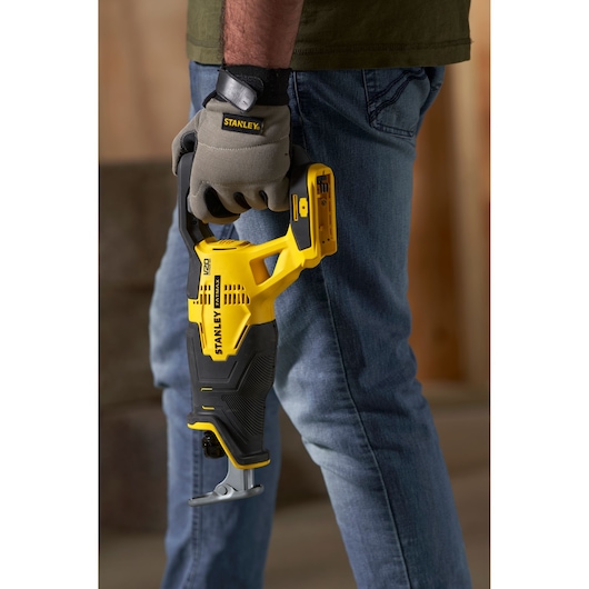 Stanley SFMCS300D1K reciprocating saw held by gloved hand, yellow and black, outdoor context