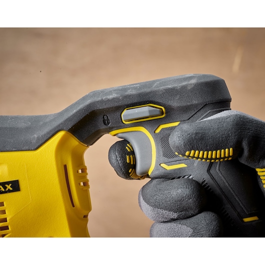 STANLEY SFMCS300D1K power tool handle close-up, yellow and black, gloved hand pressing trigger.