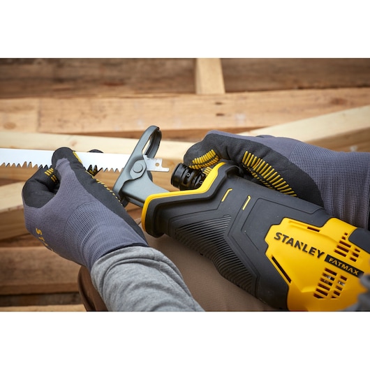 STANLEY SFMCS300D1K reciprocating saw close-up, yellow and black, blade being installed by gloved hands.