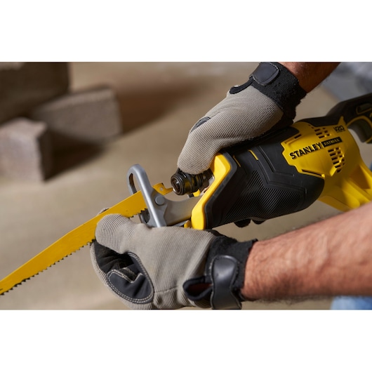 STANLEY SFMCS300D1K reciprocating saw close-up, yellow and black, gloved hands adjusting blade.