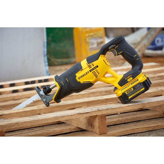 STANLEY SFMCS300M1K cordless reciprocating saw with yellow and black body on wooden pallet.