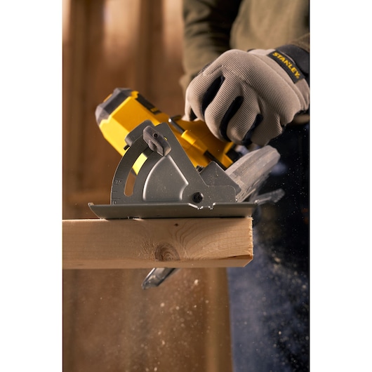 STANLEY SFMCS500D1K cordless circular saw cutting wood, worker wearing STANLEY gloves, close-up action.