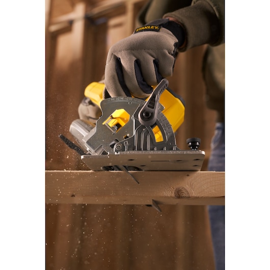 Photo of STANLEY SFMCS500D1K circular saw cutting wood, gloved hand holding saw, woodworking in progress.