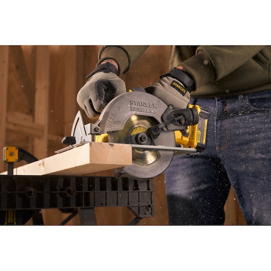 Photo of STANLEY SFMCS500M1K circular saw cutting wood, held by person wearing gloves during woodworking.