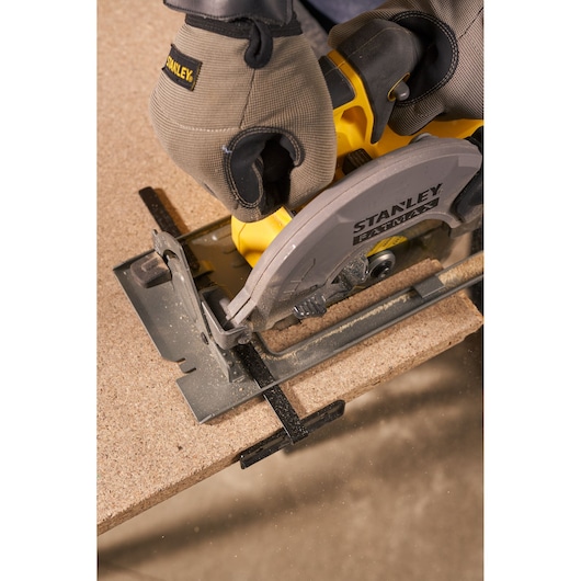 Photo of STANLEY SFMCS500M1K circular saw cutting wood, close-up view showing safety gloves in use.