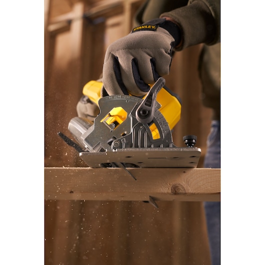 STANLEY SFMCS500M1K circular saw in use cutting wood, close-up side view with sawdust flying.