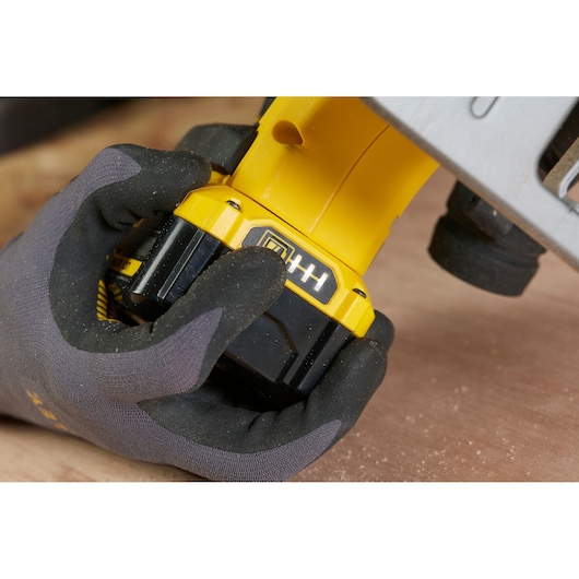 STANLEY SFMCS500M2K power tool battery being held by gloved hand, close-up on battery indicator.