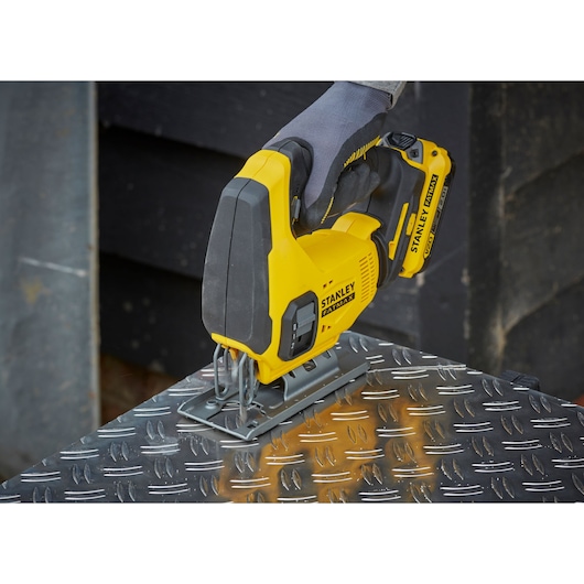 Photo of STANLEY SFMCS600D1K cordless jigsaw cutting metal, yellow and black power tool in use.
